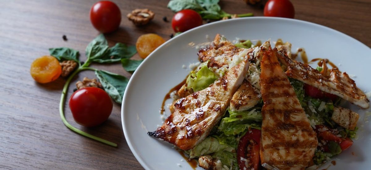 Delicious grilled chicken salad served with fresh tomatoes and walnuts on the side.