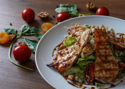 Delicious grilled chicken salad served with fresh tomatoes and walnuts on the side.